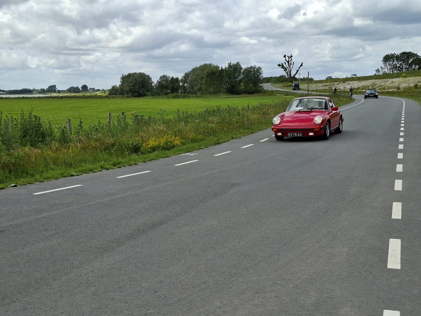 Een rode klassieke Porsche 911 op de dijk