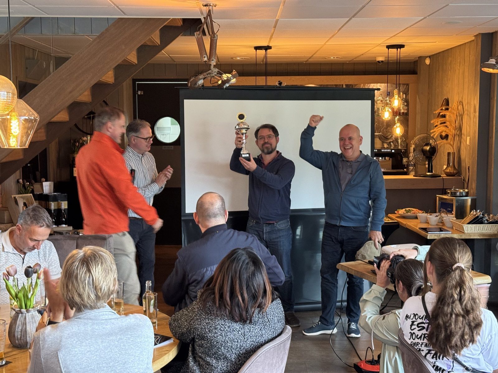 De winnende equipe houdt de beker omhoog tijdens de prijsuitreiking